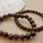 Bracelet élastique composé de boules de Véritables pierres naturelles d’Oeil de Tigre Rouge polies. Sa vibration entraîne la prise de conscience et l’entreprise de l’action directe contre les actions négatives. Utile comme bouclier, cette pierre est protectrice, contre les pensées négatives dirigées vers soi, ou encore, les influences des énergies telluriques, etc. Elle agit un peu comme un miroir: elle fait prendre conscience à l’émetteur du négatif et du mal qu’il se fait ou qu’il fait subir à autrui. Plusieurs Diamètres disponibles Bracelet en pierre naturelle, fil élastique renforcé, fabrication artisanale française.