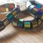 Bracelet Elastique composé en d’hématite et Titane en 1/2 Cylindre ou barrettes de 10mm. Pour précision , le titane est l’élément chimique de numéro atomique 22, de symbole Ti. La variante titanium, bien qu’attestée en français depuis 1872, est considérée comme un anglicisme incorrect. C’est donc le même métal sauf que « titane » est le mot en français, et « Titanium » est le mot en anglais. Bracelet barrettes hématite et titane obtenu par pulvérisation d’une fine couche de titane, fil élastique renforcé, fabrication artisanale française. Dimension : Perle de 10 mm