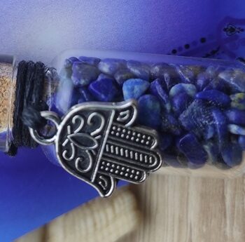 Fiole cadeau en verre sur corde lapis lazuli et khamsa* Matériel : Gemme - Lapis Lazuli Dimension  de la fiole : hauteur 36 mm Poids fiole : 15 gr Poids Total : 20 gr Emballage : Plastique Pays d'origine : Inde *Ce produit est sans nickel, sans plomb et sans cadmium; ce qui signifie donc que ces éléments ne sont pas présents ou dans les quantités limitées autorisées dans les normes européennes de sécurité des produits (REACH).